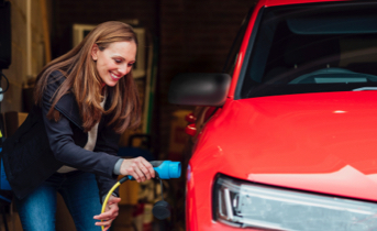 Woman charging red electric vehicle
